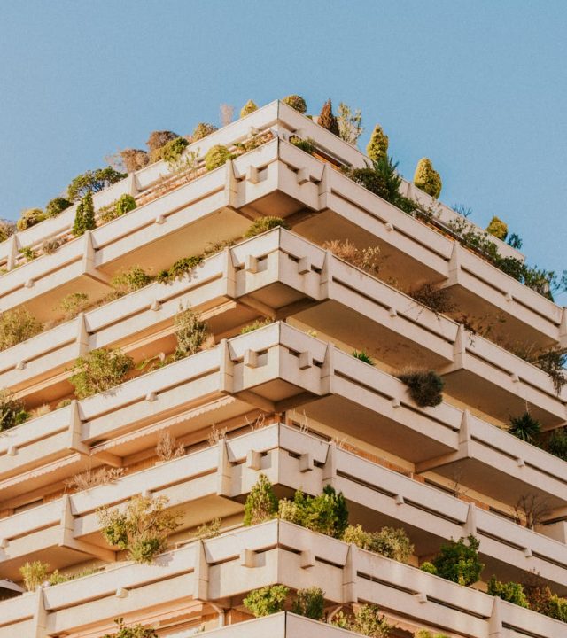 A modern building in Toulouse showcases green architecture with lush balconies filled with plants.